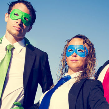 Three people in business suits wearing superhero masks and capes